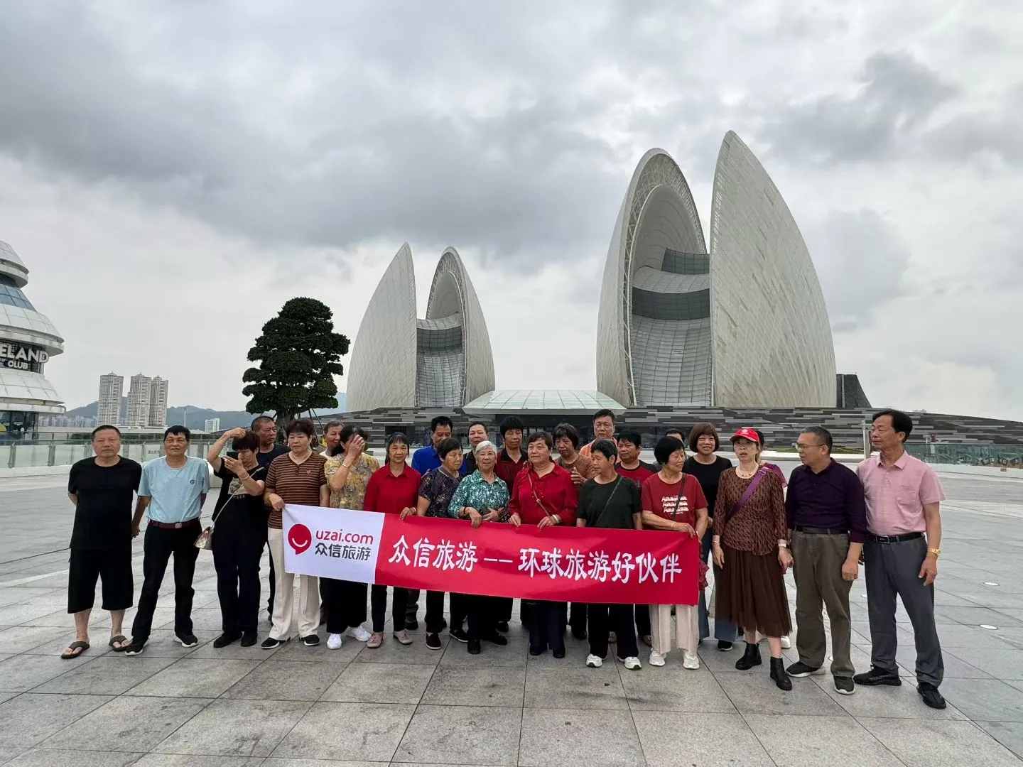中老年游客团队在城市地标建筑前集体合影